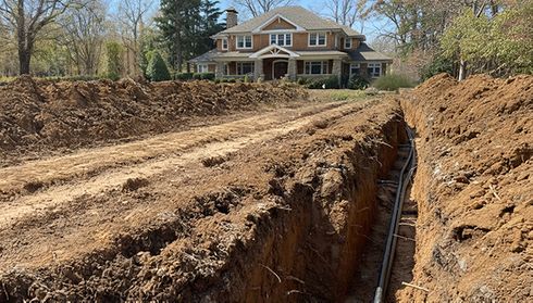 Geothermal heat pump installation trenching near a residential property