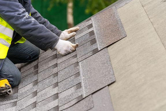 Roofer installing asphalt shingles during a full roof tear-off and replacement