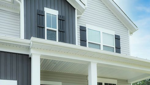 Gray vinyl siding on a two-story house exterior with black shutters