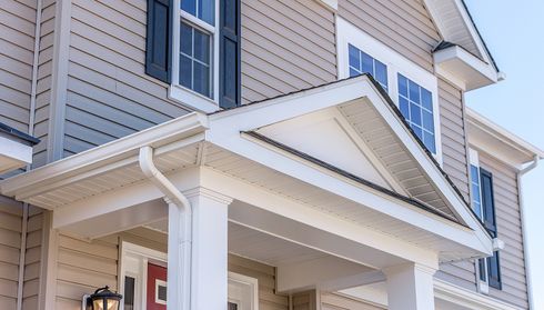 Beige vinyl siding on a house gable with white trim