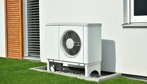 Residential air source heat pump installation next to a house
