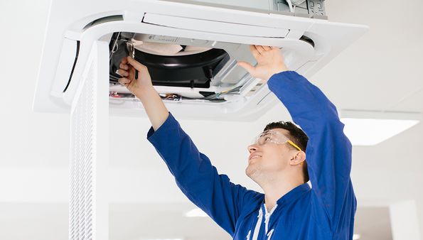 Technician fixing a ceiling air conditioning unit