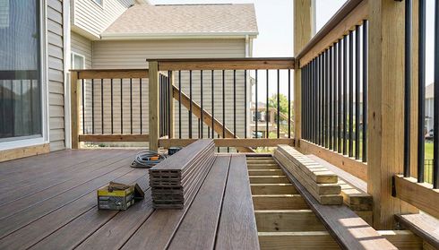 Partially constructed outdoor deck with wood boards and railing