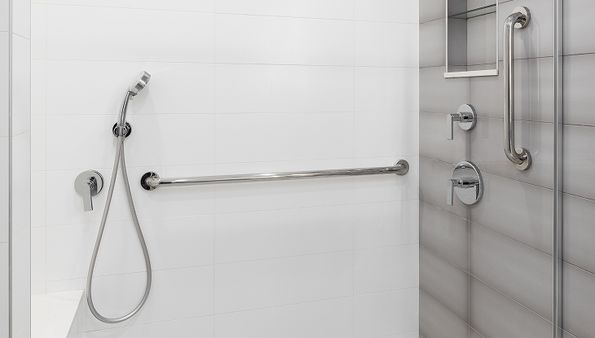 White tiled shower with handheld showerhead, metal grab bars, and control knobs