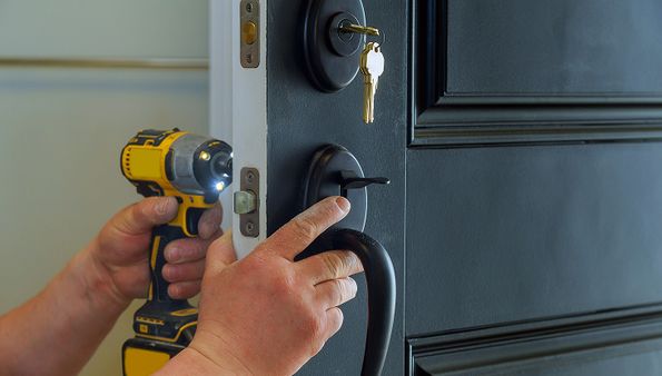 A person installing a black door handle using a drill