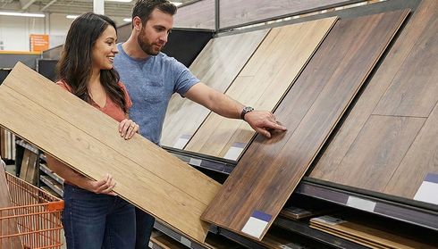 Couple comparing laminate floor planks in store