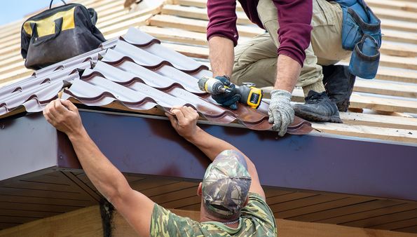 Roofers installing metal tile roofing panels
