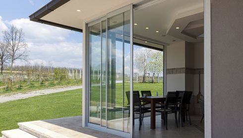 Modern glass sliding patio doors by outdoor dining area