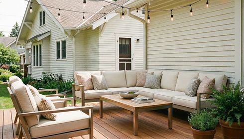 A cozy deck with cream sofas, a wooden table, potted plants