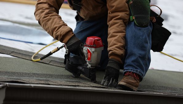 Roofer installing asphalt shingles during a roof replacement