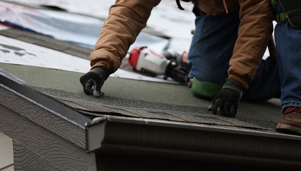 Contractor installing new roofing materials after tearing off the old roof during a roof replacement project