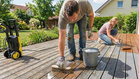 Two people cleaning a wooden deck