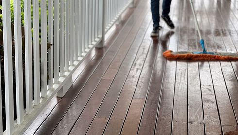 Person mopping a wet wooden deck